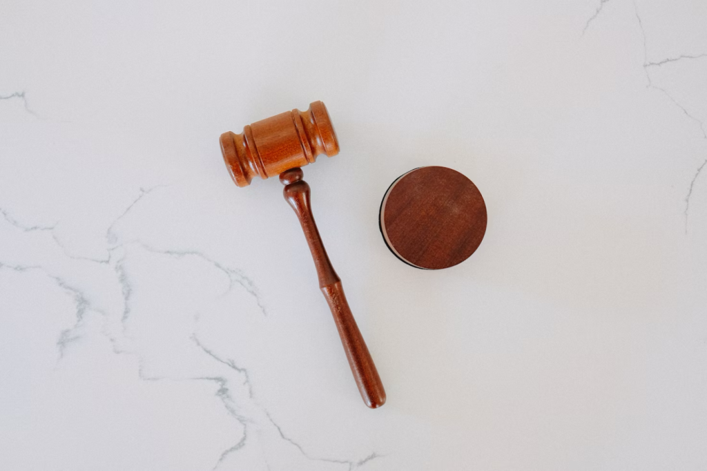 a wooden gavel and block placed against a white marble backdrop
