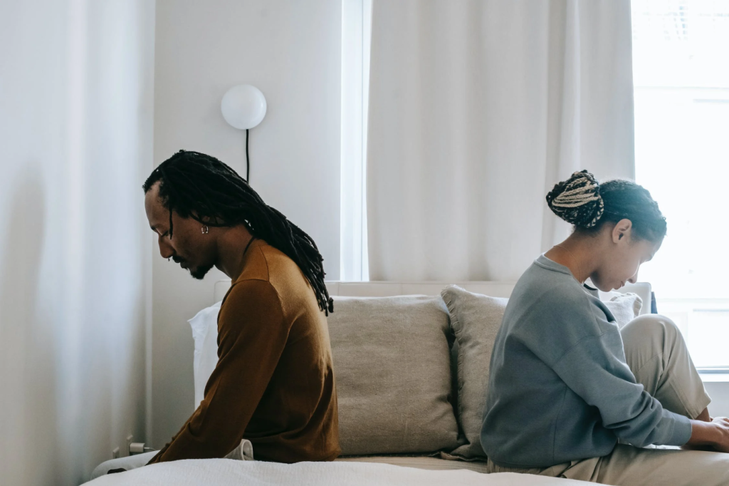 a couple sitting in opposite directions on a bed