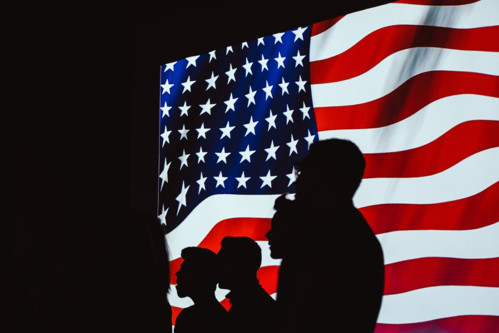 Silhouette of people beside USA flag.