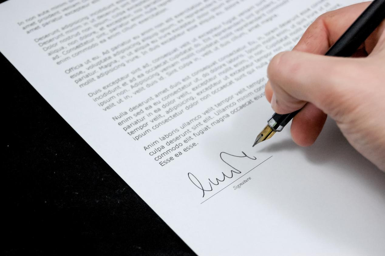 A person signing a piece of paper