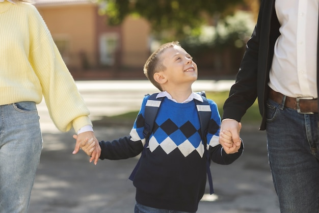 Smiling child holding hands with two adults