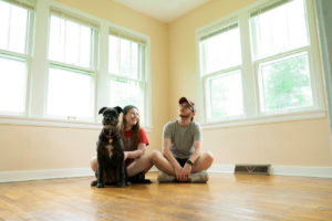 Couple sitting on the floor with their dog in an empty room