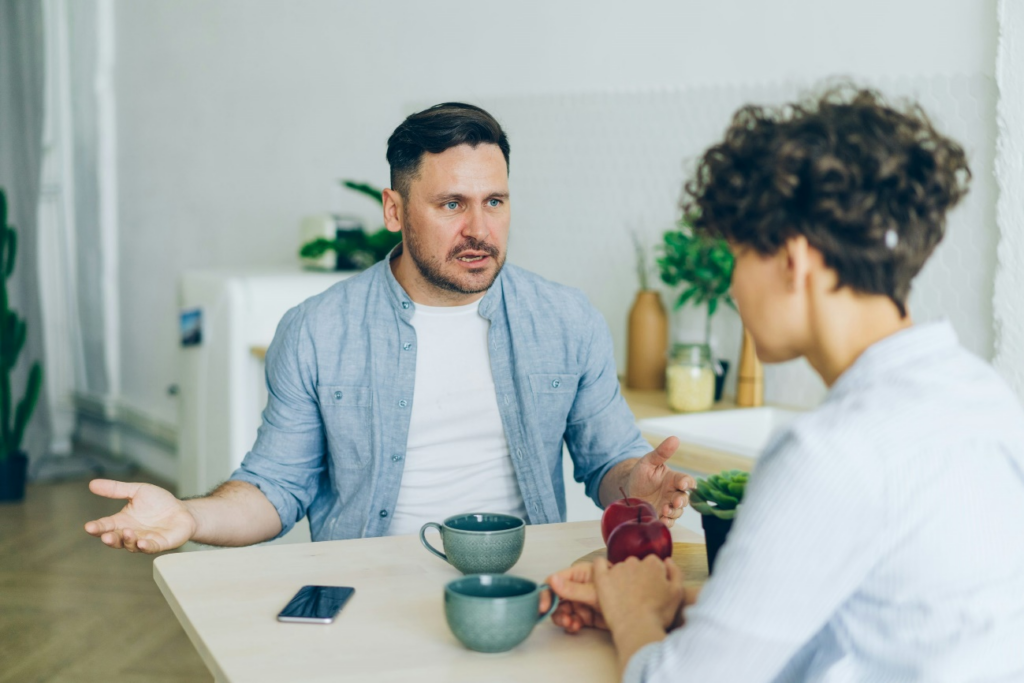 A father and mother having a serious conversation at a table by https://unsplash.com/photos/a-man-sitting-at-a-table-talking-to-a-woman-yrSta3T5GDs