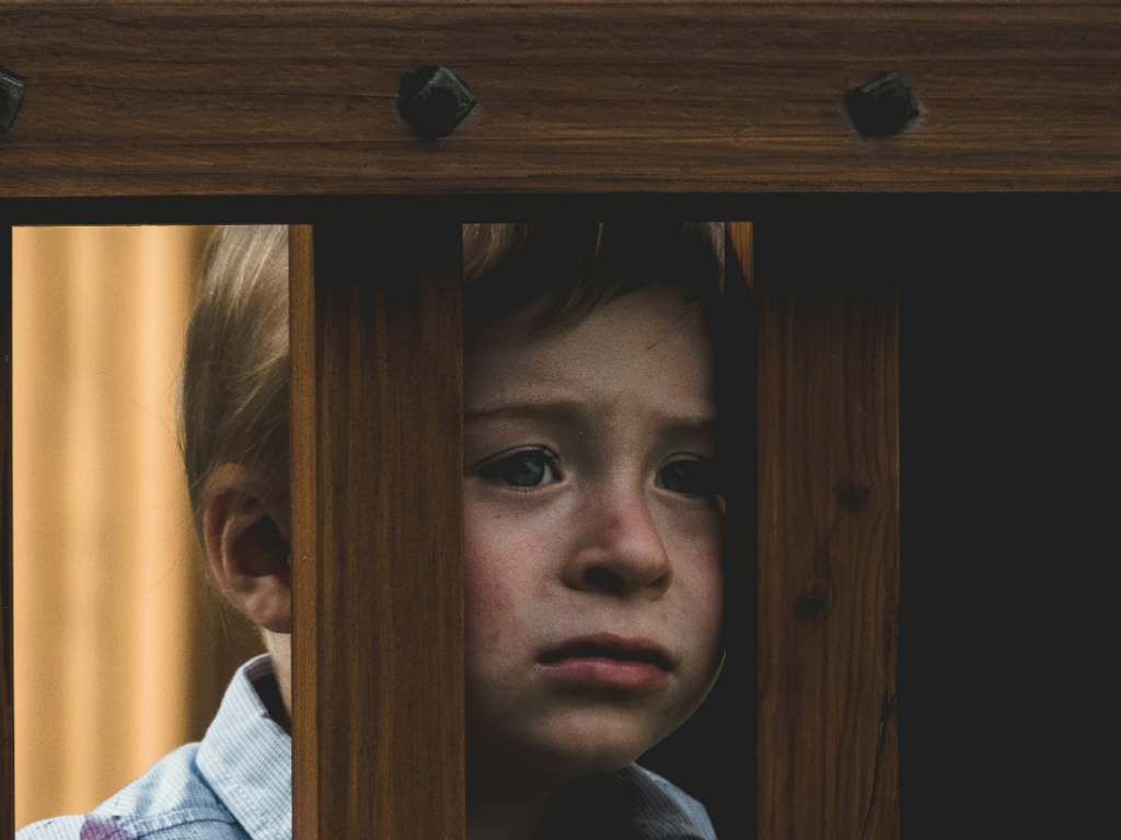 Sad child looking through wooden bars by https://unsplash.com/photos/boy-leaning-on-brown-wooden-railings-wZAQJLjDWNY