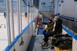 A father and his son are watching an ice hockey game