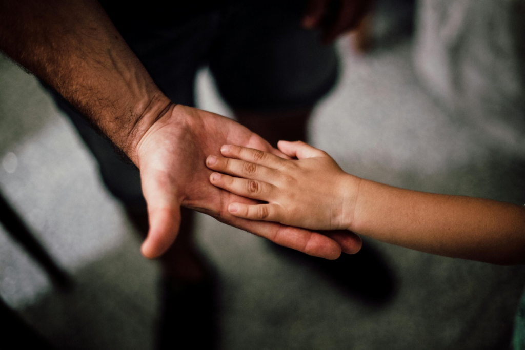 A child placing his hand on his father's hand