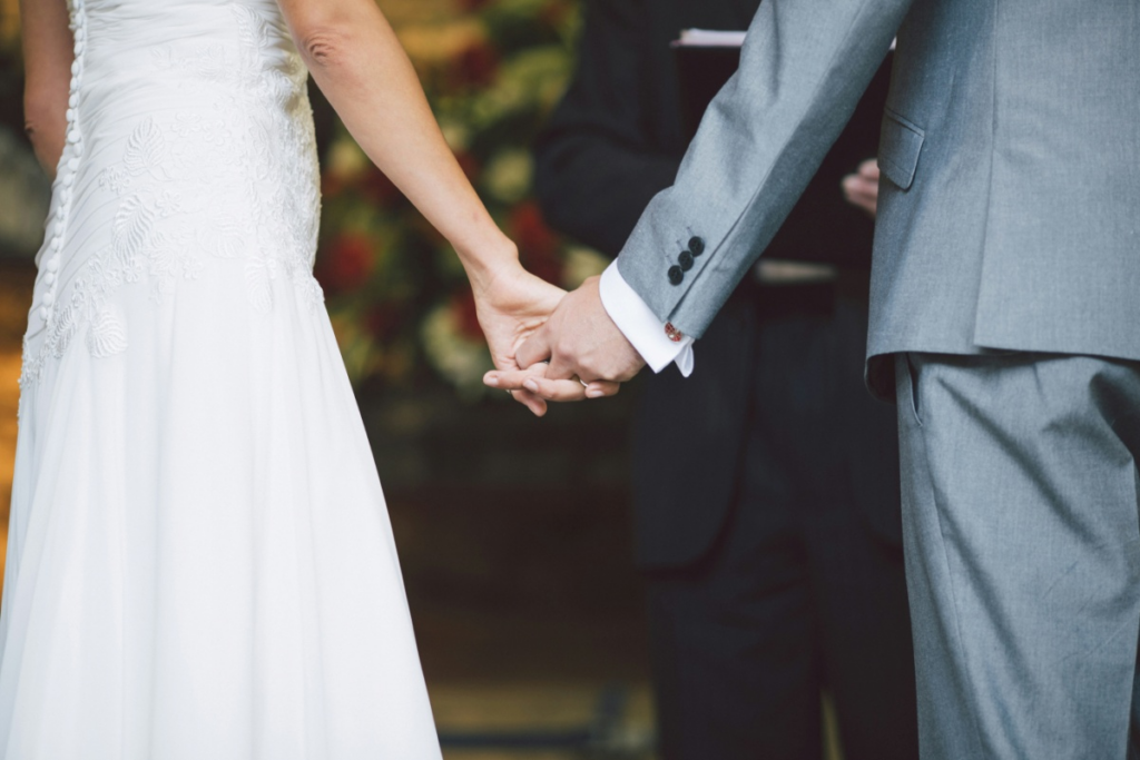 A couple holding hands at their wedding