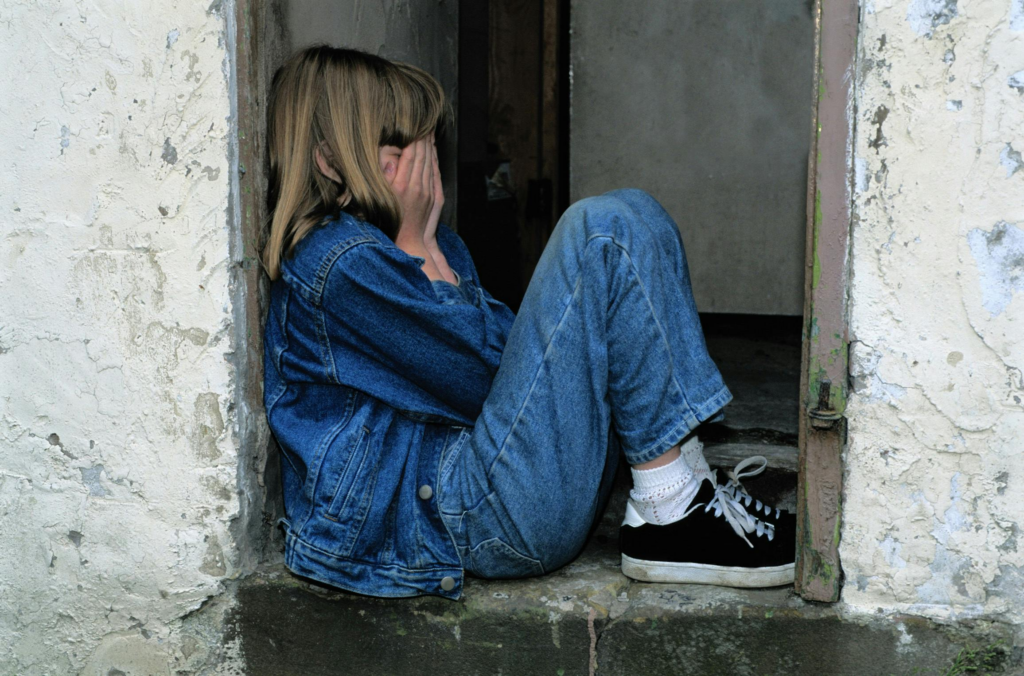 A kid sitting with their face covered